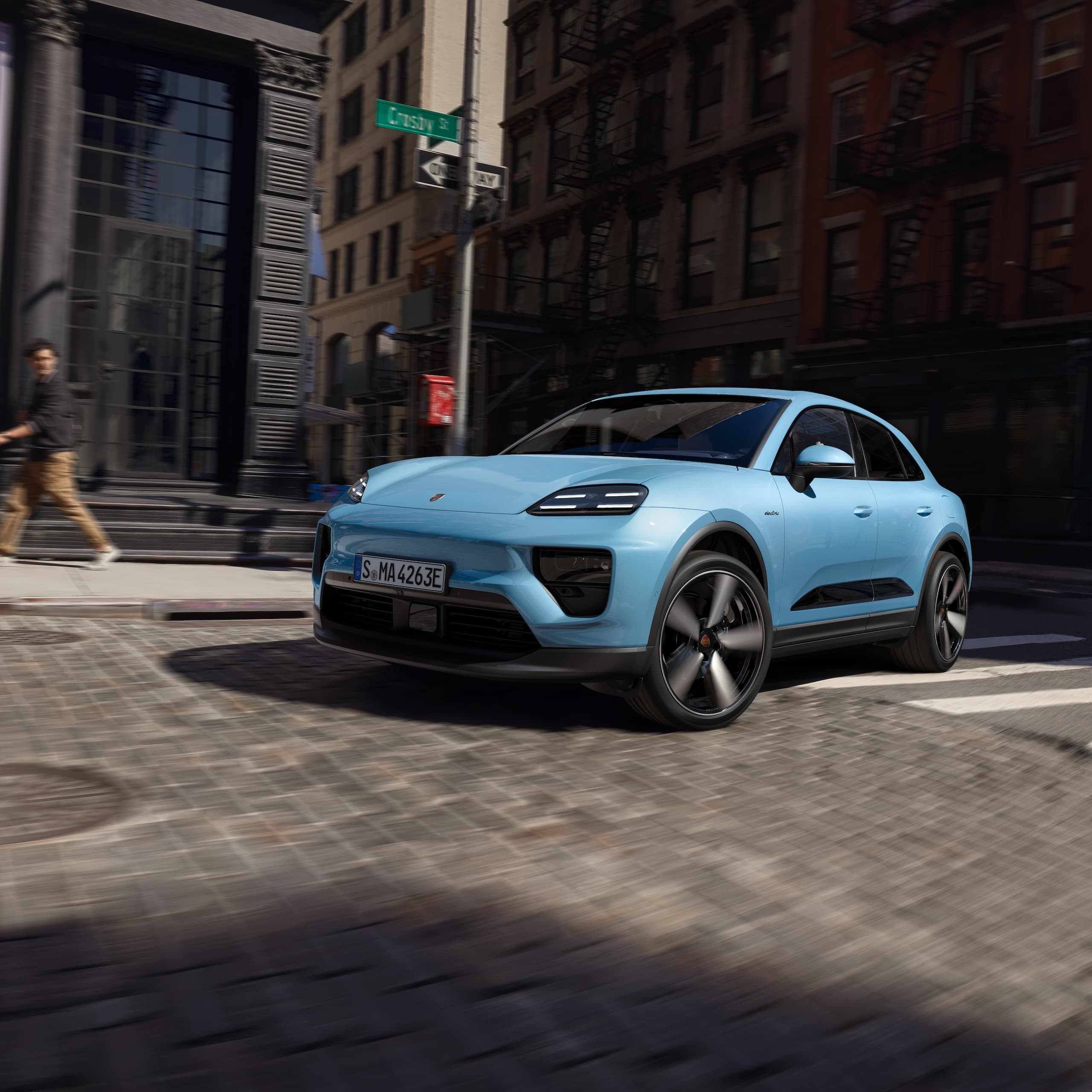 A Porsche all-electric Macan driving down a road in an urban scenario.